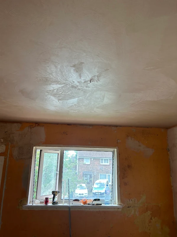Orange walls and a rough ceiling around the window