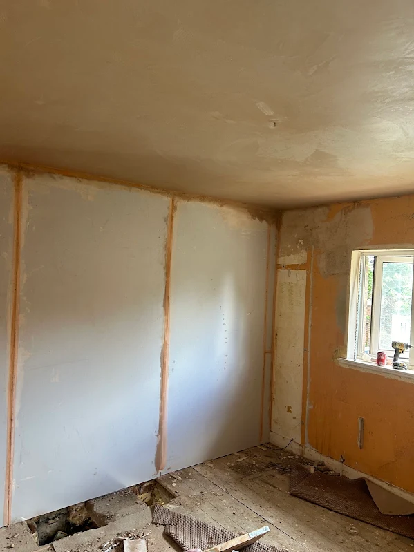 Plasterboard fixed and taped on a wall, before the skim.